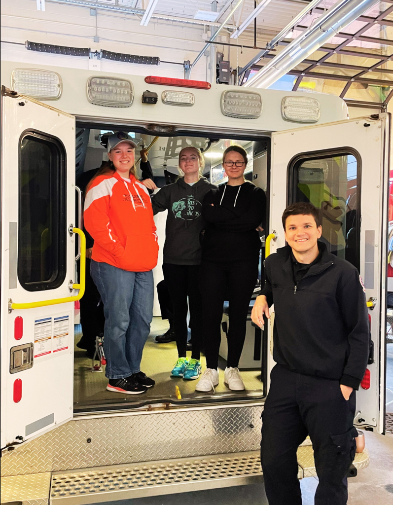 Three Hillsboro students stand with EMT